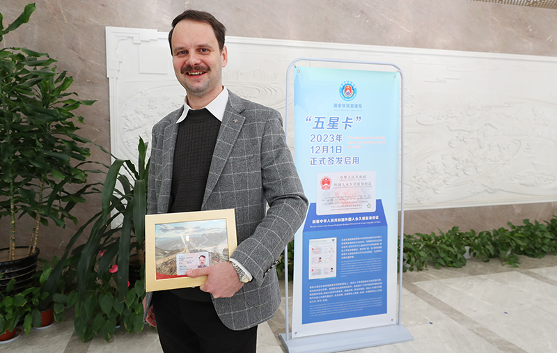 On December 1, 2023, Berezkin Rostislav from Russia proudly displays the newly issued Foreign Permanent Resident ID Card, framed as a keepsake, at the exit-entry administration bureau of the Shanghai Public Security Bureau in Shanghai, eastern China. [Photo/Xinhua]