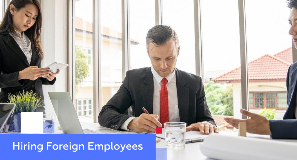 Three professionals in an office meeting reviewing paperwork — illustrating hiring foreign employees in China