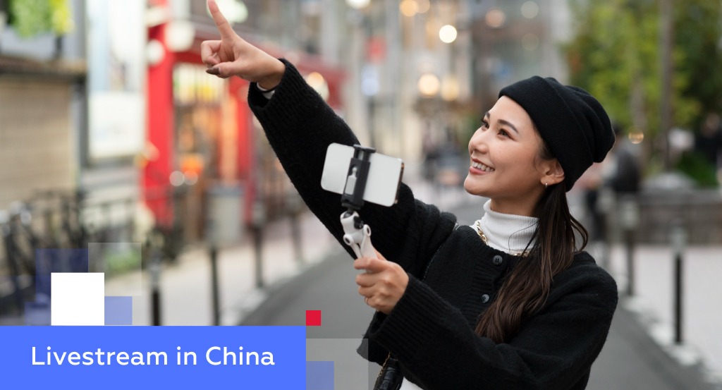 Young Chinese livestream host filming with a smartphone gimbal on a shopping street — illustrating livestream commerce in China